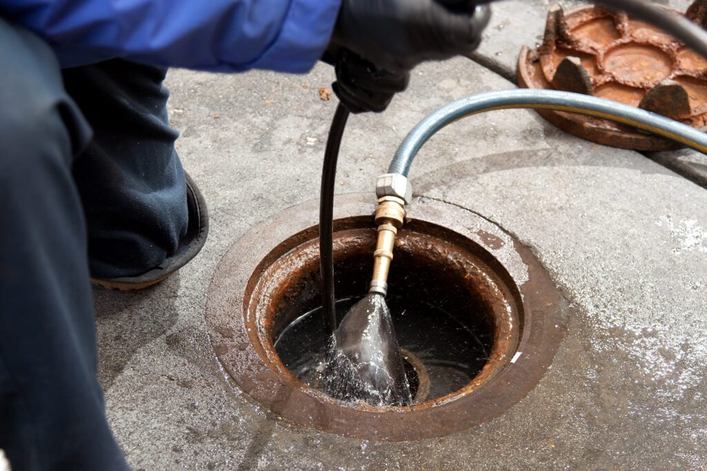 Plumber hydro jetting a sewer line through a manhole in Loma Linda