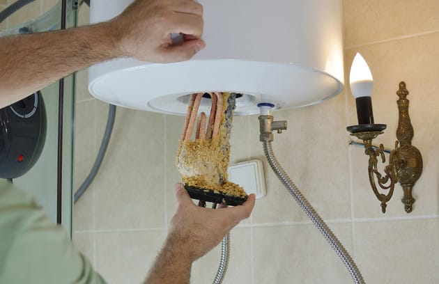 Technician removing mineral buildup from a water heater in Loma Linda